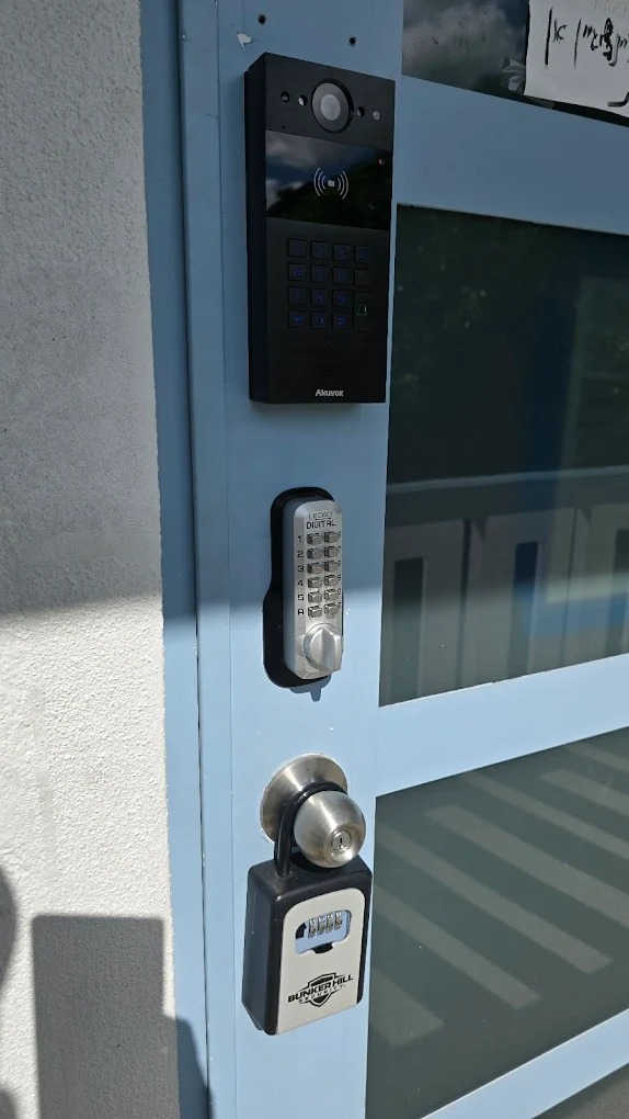 Facial recognition access control terminal mounted at building entrance showing camera display with employee identification
